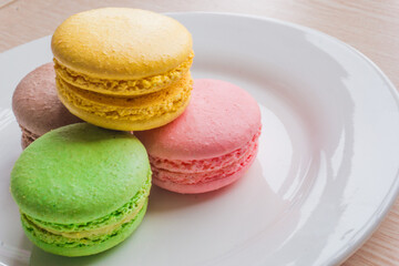 Close up colorful macarons cakes. Macaroons isolated on a white plate. 
A french sweet delicacy.