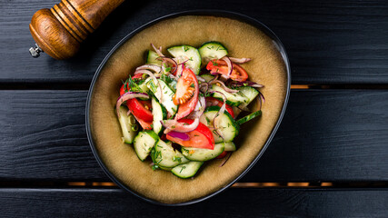 Fresh tomatoes with red onion, cucumber and spices in a ceramic bowl. Concept for a tasty and healthy appetizer
