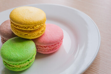 Close up colorful macarons cakes. Macaroons isolated on a white plate. 
A french sweet delicacy.