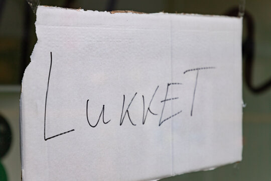 sign with the handwritten danish word lukket (means closed) on a door of a retail in Denmark during corona pandemic