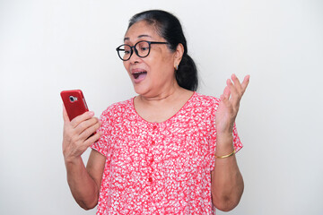 Elderly Asian woman showing excited expression when looking to her mobile phone