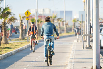 latin man riding a bicycle on bikeway at sunset in La Serena