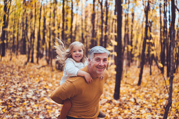 Fototapeta premium Father and daughter having fun in the autumn colorful forest