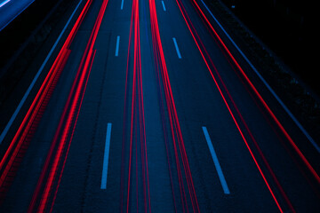 Long exposure by night of red car light streaks on the highway