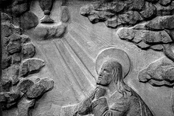 Ancient statue of Jesus Christ prays on Mount Tabor. Christianity, religion, suffering, death and resurrection concept. Black and white image.