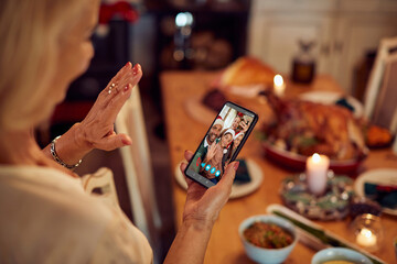 Close-up of senior woman congratulates Christmas to her family via video call over smart phone.