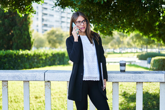 Busy businesswoman with laptop talking on smartphone