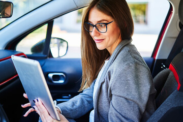 Positive woman using tablet in car