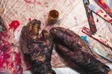 Fototapeta na wymiar Black mittens from paint. Artist's mittens. Creative mess with paints.