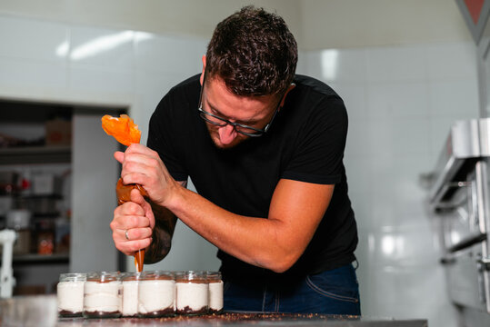 Young man decorating yummy layer dessert with caramel sauce
