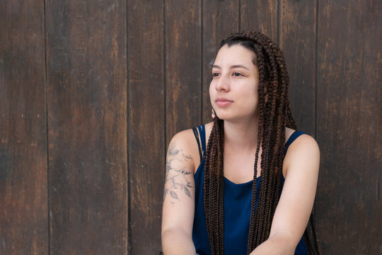 Hispanic woman sitting near wooden wall