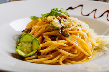 Spaghetti alla nerano con zucchine fritte e provolone del monaco serviti in un ristorante 