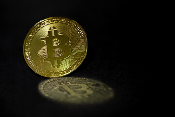 Golden bitcoin reflects in light on dark surface