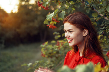 cheerful woman in nature near a tree with berries