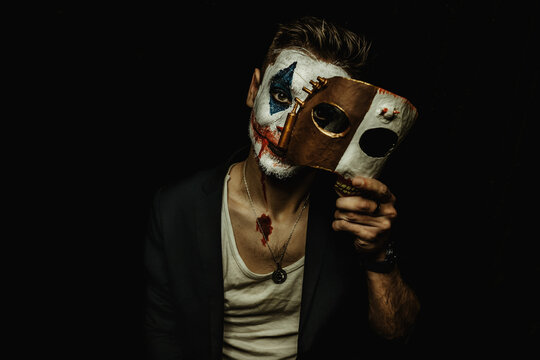A young man with makeup on his face shows different emotions. Place for the text. Black background