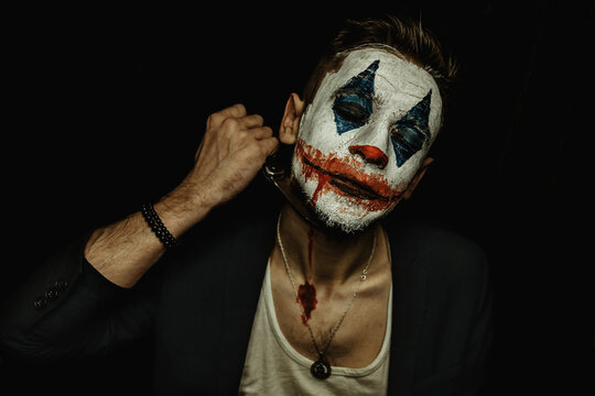 A young man with makeup on his face shows different emotions. Place for the text. Black background