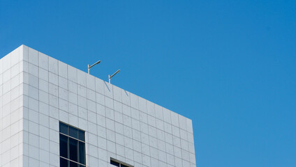 Obraz premium a skyscraper building that has a white ceramic wall with a blue sky background. the high building in the urban area.