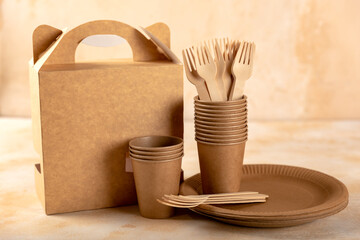 Eco-friendly disposable paper tableware. Paper cup, wooden forks, paper plate, cardboard box on a...