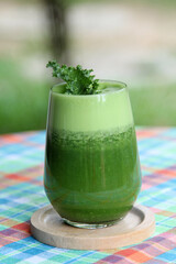 The vegetable green smoothie decorated by kale leaves in a clear glass.