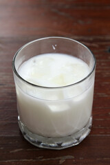 The iced milk in clear glass on the wooden table.