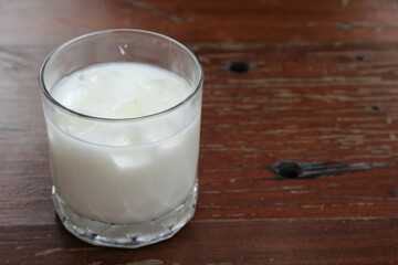 The iced milk in clear glass on the wooden table.