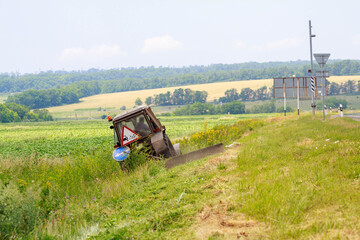 Fototapeta premium Tractor with a mechanical mower mowing grass on the side of the asphalt road
