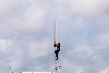 Worker disassembling an antenna on the roof of a building