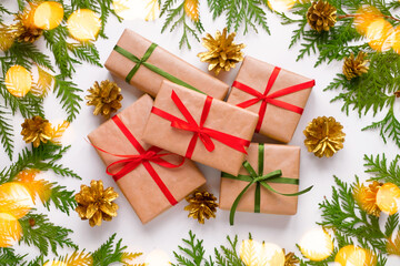 Group of Christmas presents wrapped in kraft paper surrounded of thuja branches on white background. New year background with lighten gold bokeh