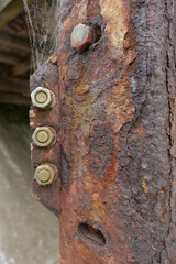 Close up of rusty old metal pillar with steel nuts and bolts