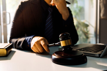 Justice and law concept.Male judge in a courtroom with the gavel, working with, computer and docking keyboard, eyeglasses, on table in morning light