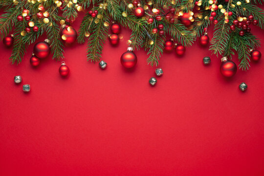 Red Christmas background with fir branches, lights and decorations .