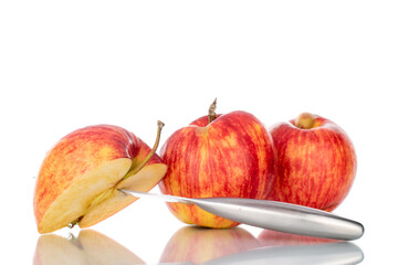 One half and two whole organic juicy apples with a metal knife, close-up, isolated on white.