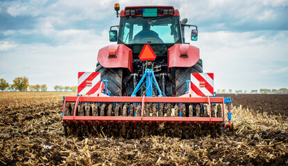 Obraz premium Farmer working in the field with a tractor after the harvest, preparing land for the next season. Agricultural concept