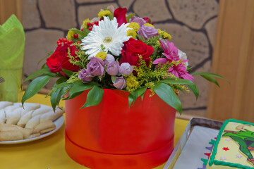 Beautiful bouquet of flowers in a box . Romantic red, white , yellow, purple roses in a red gift box to place the logo on a yellow background spring is coming,international women's day .