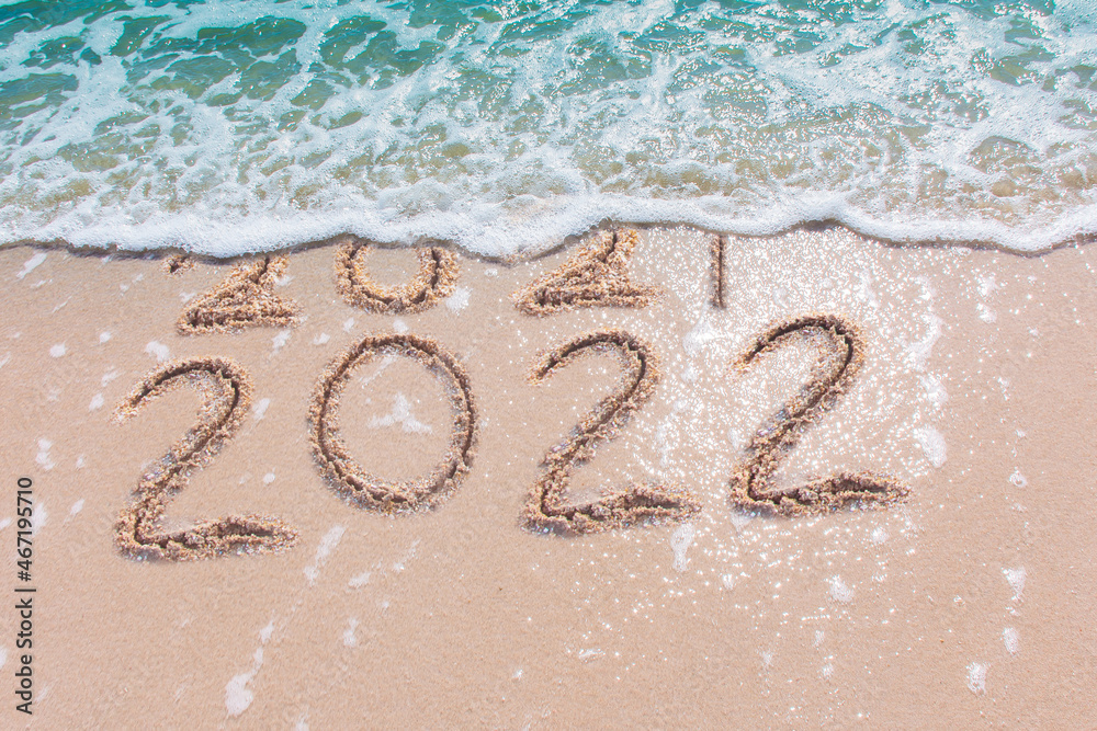 Wall mural message year 2021 replaced by 2022 written on beach sand background. good bye 2021 hello to 2022 hap
