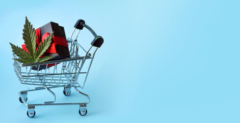 Cannabis store concept. Marijuana leaf with gift boxes in shopping cart. CBD oil products retail. Holidays sale banner