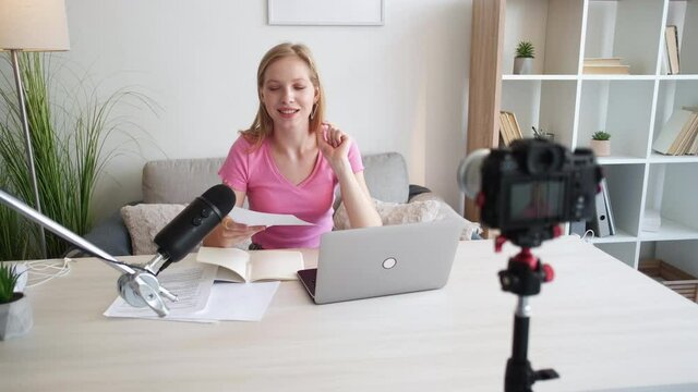 English lesson. Female teacher. Educational blog. Happy woman showing correct pronunciation of words on photo camera in light home studio interior.