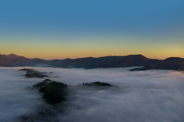 Beautiful landscape with thick mist in mountains at sunset. Drone photography