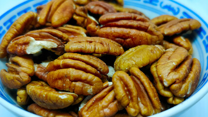 Detail view on pecan nuts in the Chinese porcelain bowl on the white background.