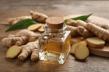 Glass bottle of essential oil and ginger root on wooden table