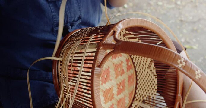 Cut in shot of Thai female farmer weave basket in traditional Thai art patterns to sell as extra income in countryside of Thailand	