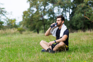 Tired exhausted dehydrated Athlete man runner drinking water bottle after workout. Sports bottle...