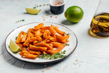 Sweet potato fries with lime and herbs on light background. top view