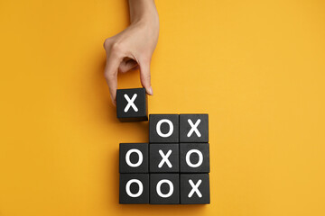 Woman playing tic tac toe game on yellow background, top view - obrazy, fototapety, plakaty
