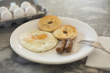 Egg sausage and bagel toast with ground black pepper on a breakfast plate.