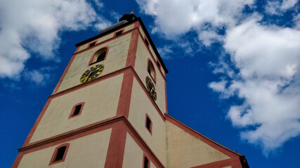 Church tower seen from the bottom up to the sky with beautiful blue color and tiny white clouds. This beautiful church is located in small town near South Bohemian city Ceske Budejovice.
