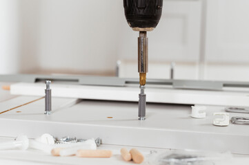 Carpenter services concept. Close up assembling kitchen furniture with cordless screwdriver