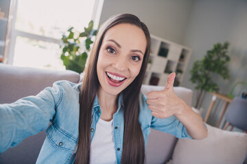 Self-portrait of attractive cheerful long-haired woman showing thumbup advert staying at home indoors