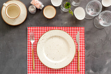 Tableware set with empty plate with dishware and glasses on napkin