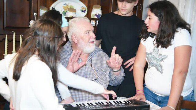 Grandfather explaining how to use electrical piano to his grandchildren at home